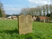 gravestone with the farm buildings beyond