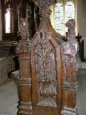 Annunciation. Mary at her prayerdesk on left, angel on right, lilies in pot in niche